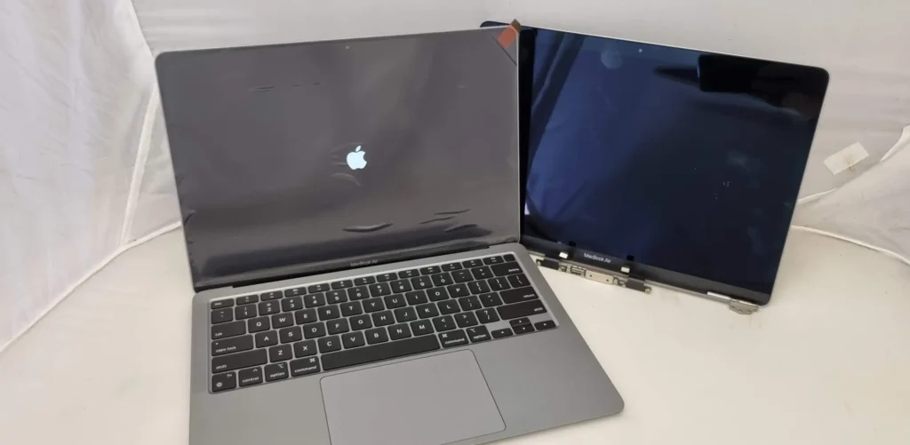 A MacBook with a detached screen panel, showing the process of replacing a damaged display.