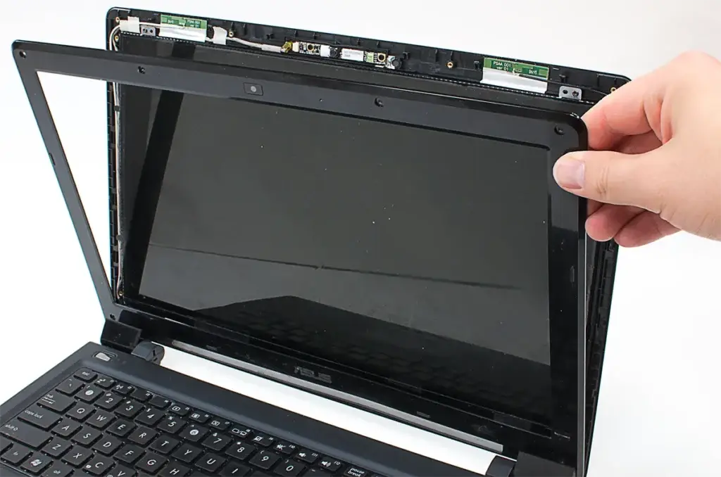 DIY laptop screen replacement in progress, with the screen being carefully removed from the frame.